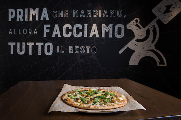 Strada pizza in front of themed pizzeria background