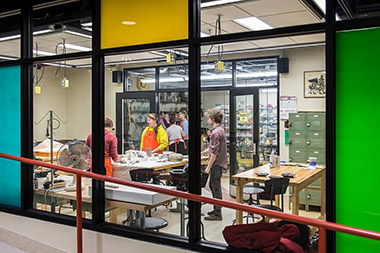 Wheelhouse Studio: View through a window into the studio, where people are collaborating on a project