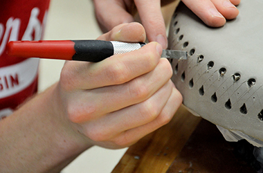 Artist carving details into a clay work.