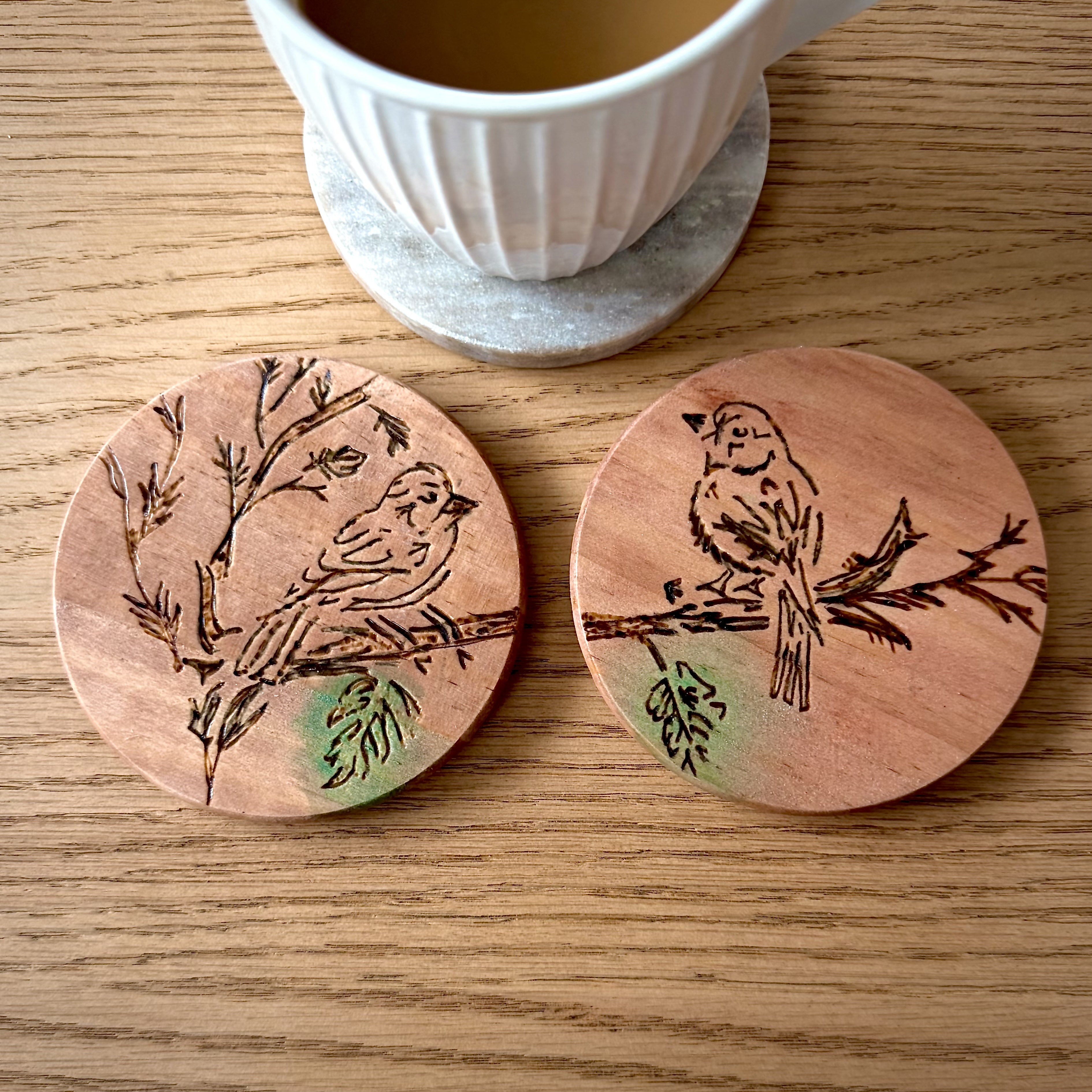 Photo of two coasters with birds engraved into them. 