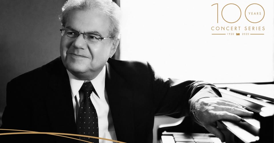 Black and white photo of Emanuel Ax sitting at a piano.