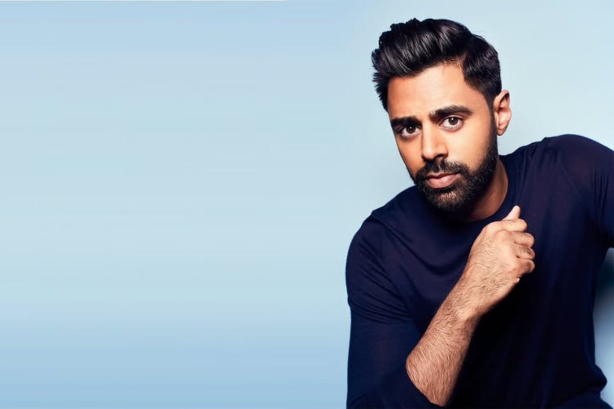 Photo of Hasan Minhaj in front of a light blue backdrop.