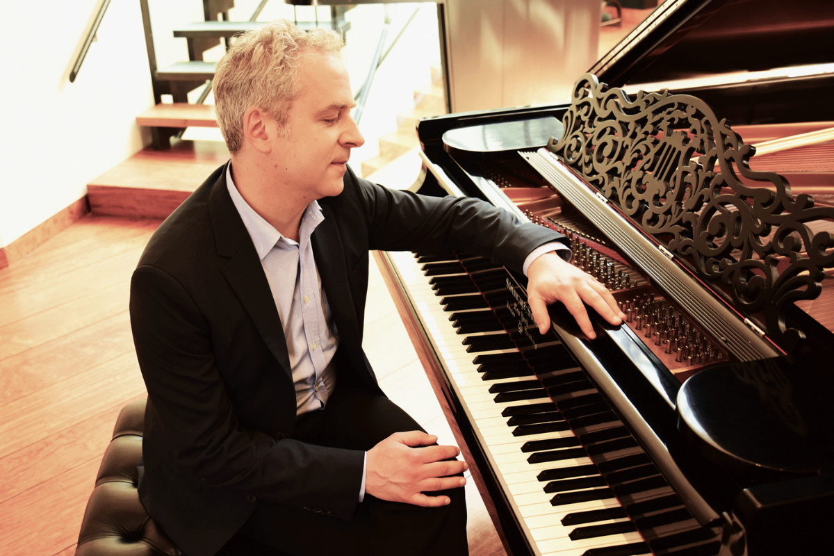 Jeremy Denk sitting at a grand piano.