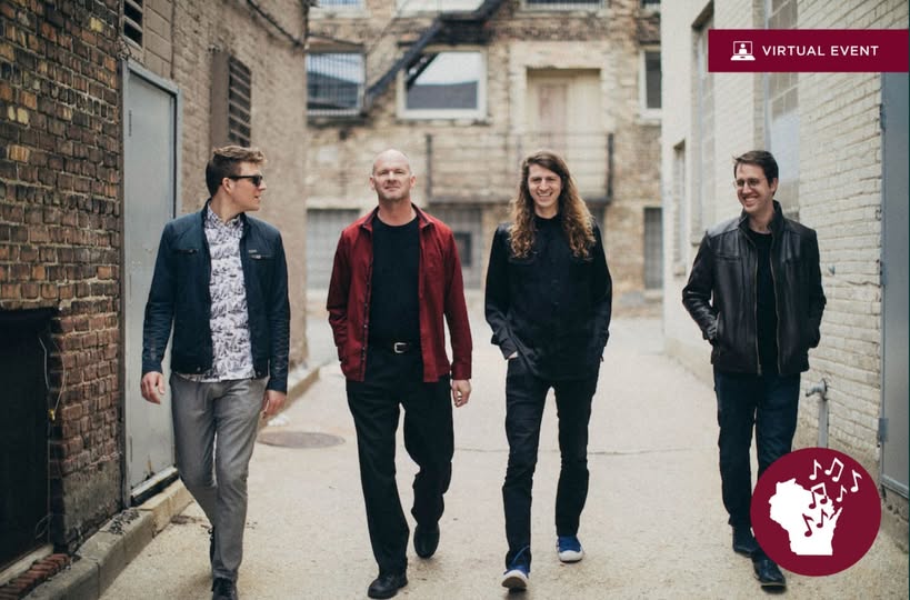 Group of four musicians walking through an alleyway.