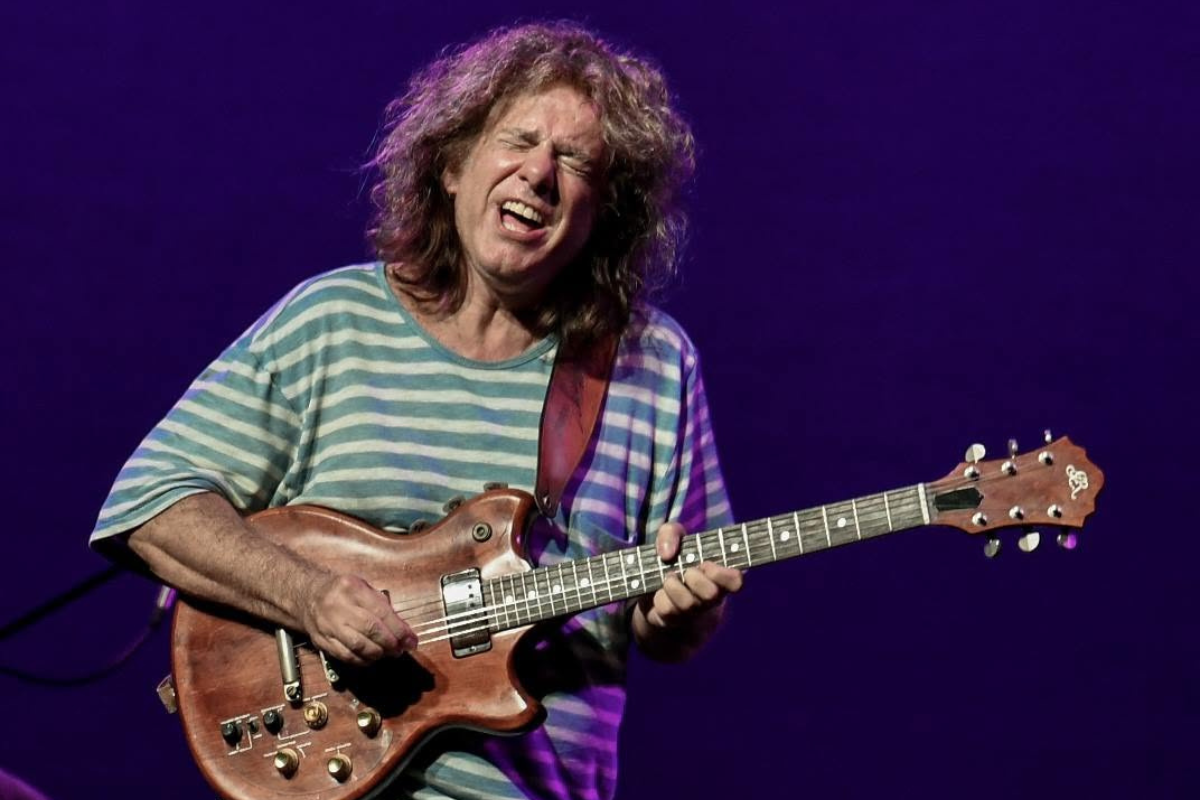 Pat Metheny playing an electric guitar on stage.