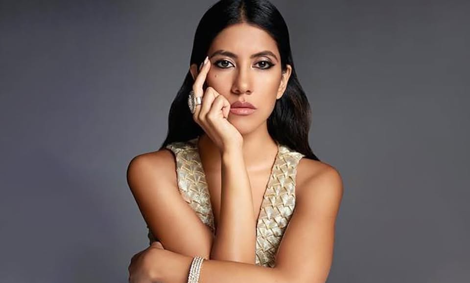 Stephanie Beatriz posing in front of a gray backdrop.