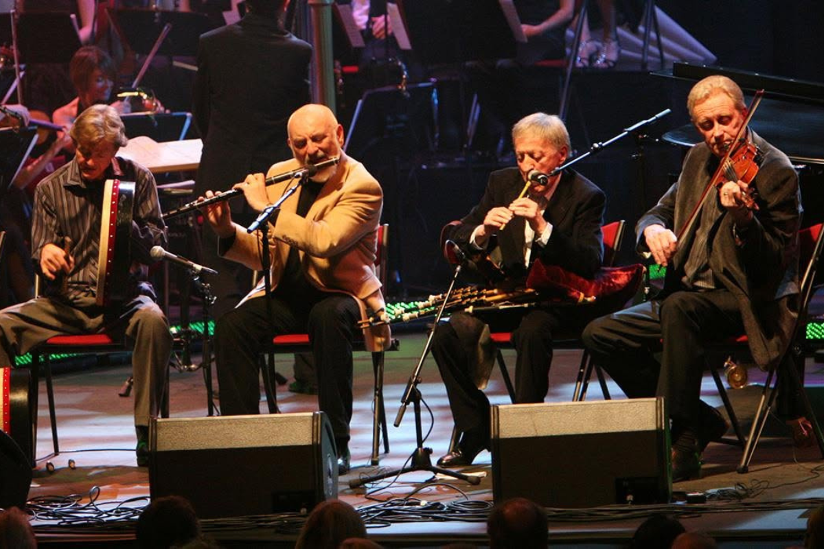 Photo of musicians sitting on stage and performing.