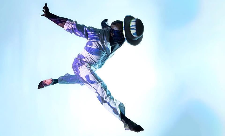A dancer leaping in front of a blue and white background.