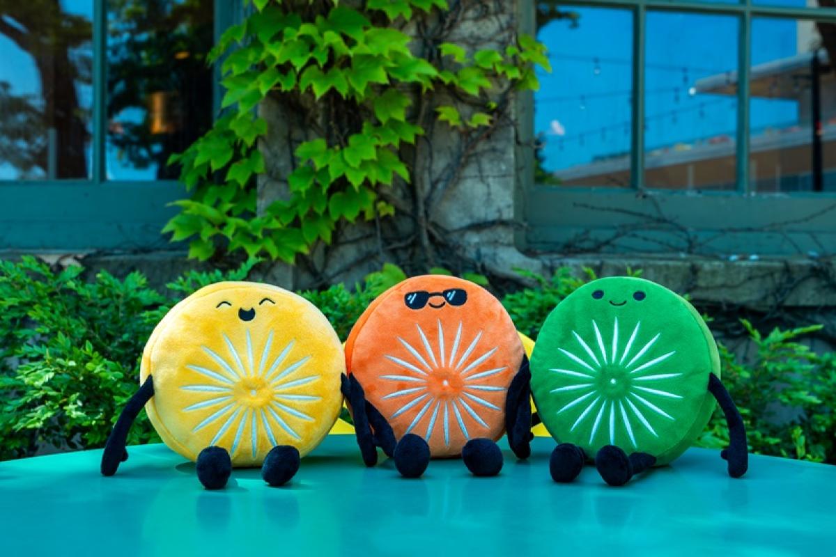 three Terrace chairlings in yellow, orange adn green sitting on green Terracetable with greenery and window behind them