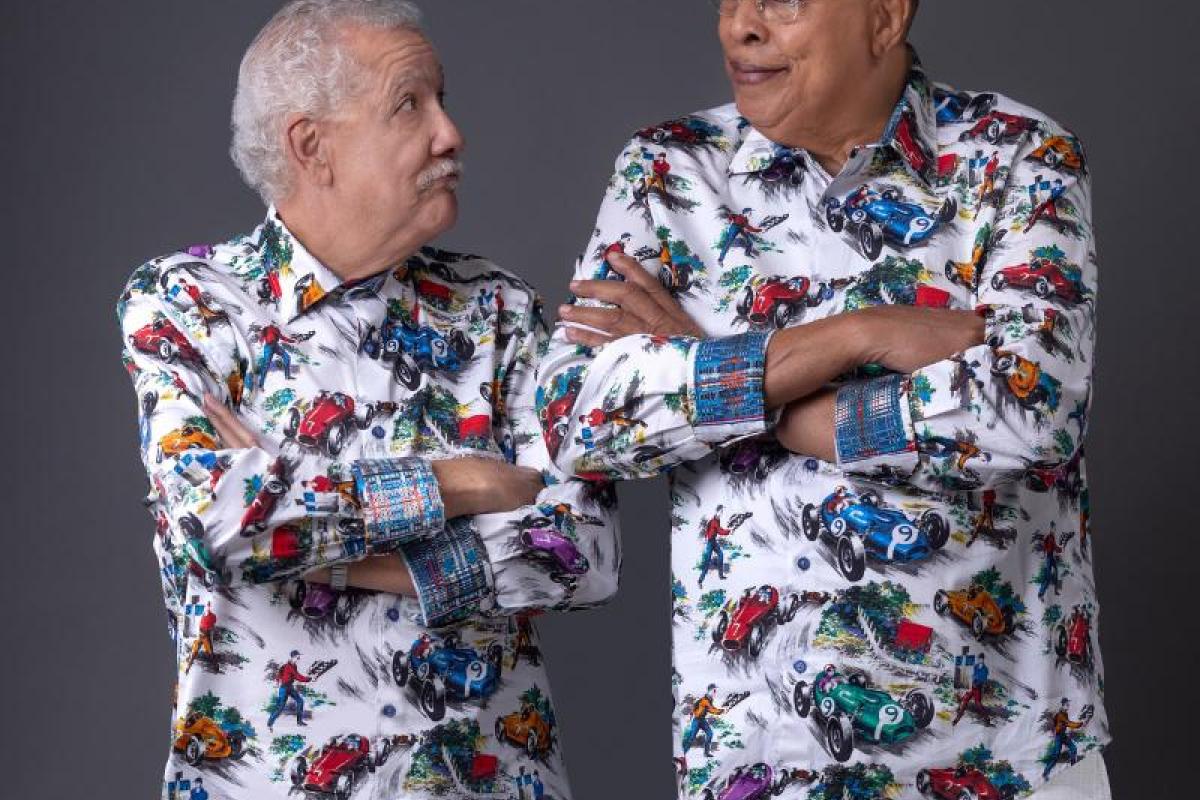Photo of Chucho Valdes and Paquito D'Rivera standing next to each other with arms crossed, both wearing colorful patterned shirts