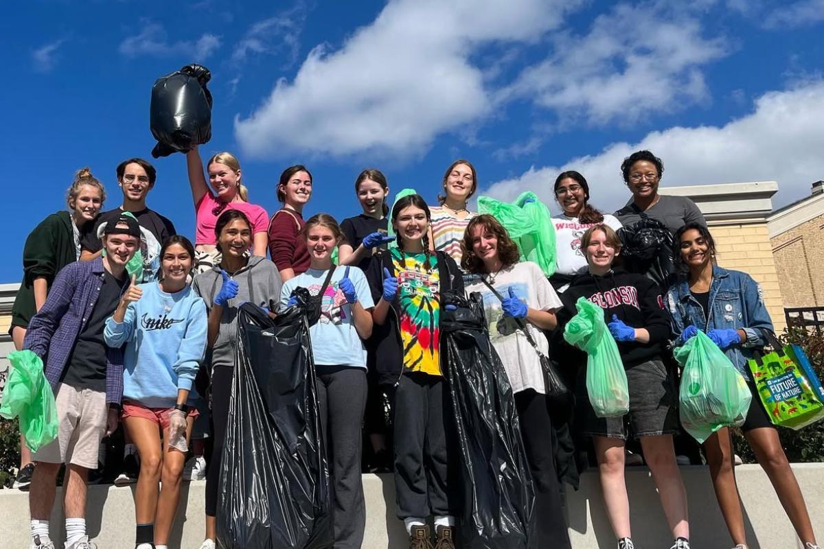 Students pose near Camp Randall with trash bags full of picked up litter.