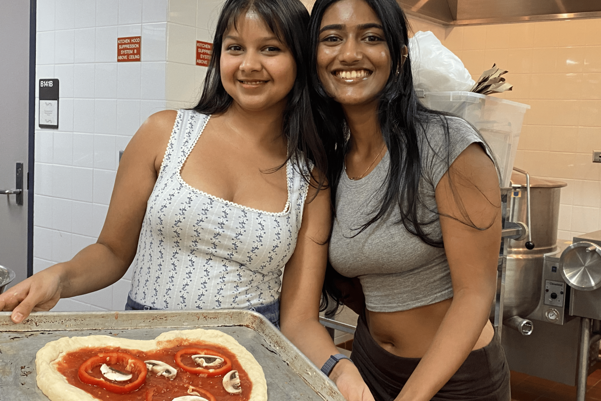 Two students show off their heart-shaped pizza before it goes into the oven during a cooking workshop.