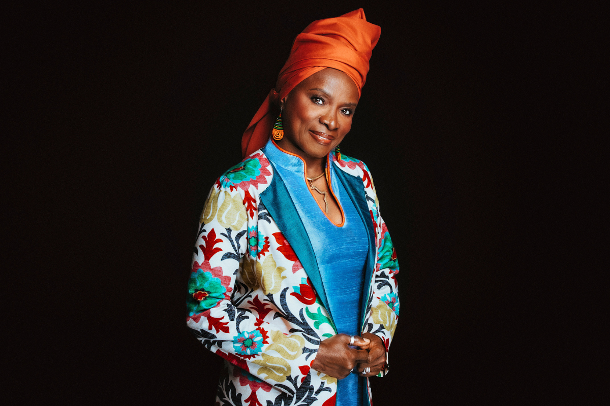 Angelique Kidjo standing in front of a black background.