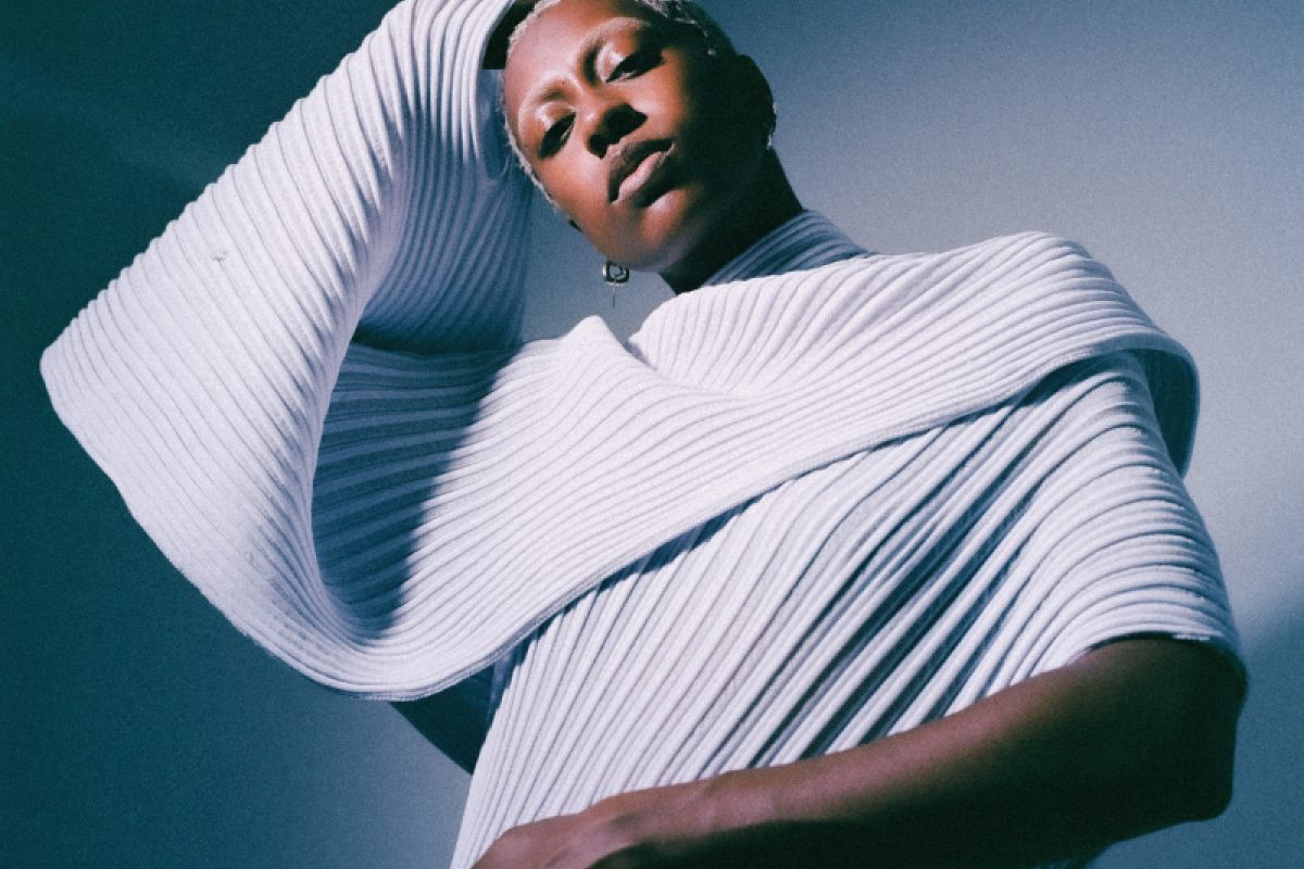 anaiis standing in front of a white and blue backdrop.