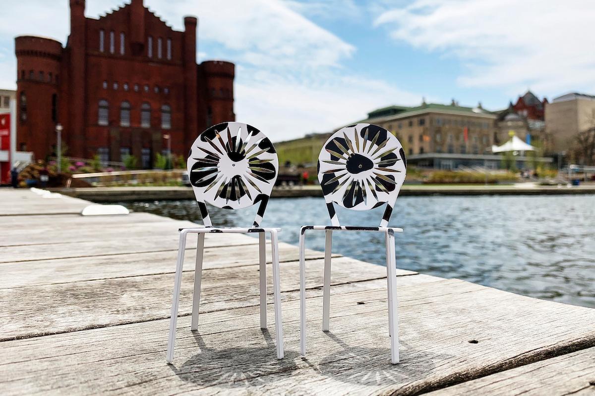Two cow print mini Terrace chairs sit on a dock near Memorial Union and Red Gym