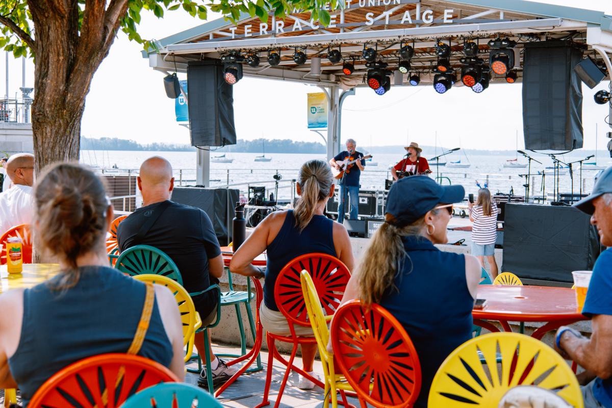 people sitting at terrace with stage and water in front of them
