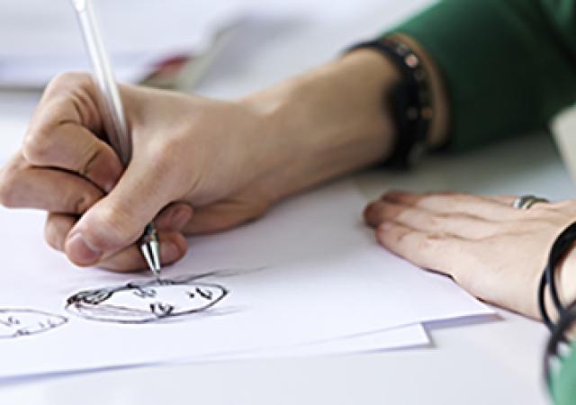 Closeup of someone drawing a face with a pen