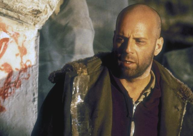 blading individual with a beard and dark jacket standing next to a 12 monkey graffiti image