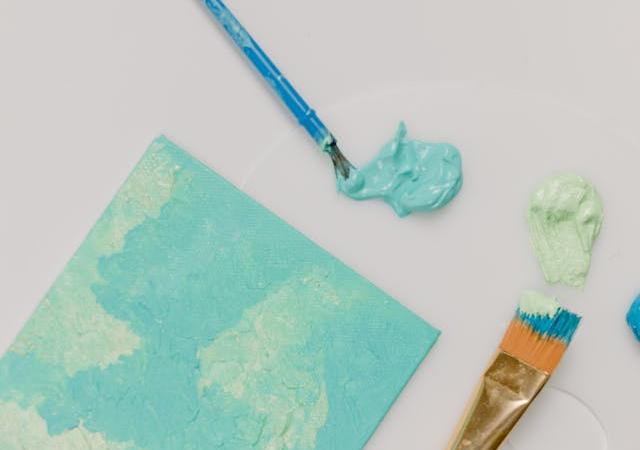 Photo of canvas, blue acrylic paint, and brushes