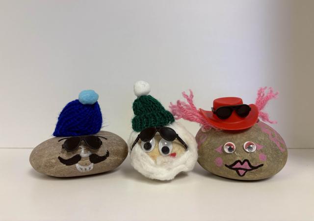 Pet rocks sitting in a row, decorated with faces, hats, etc.