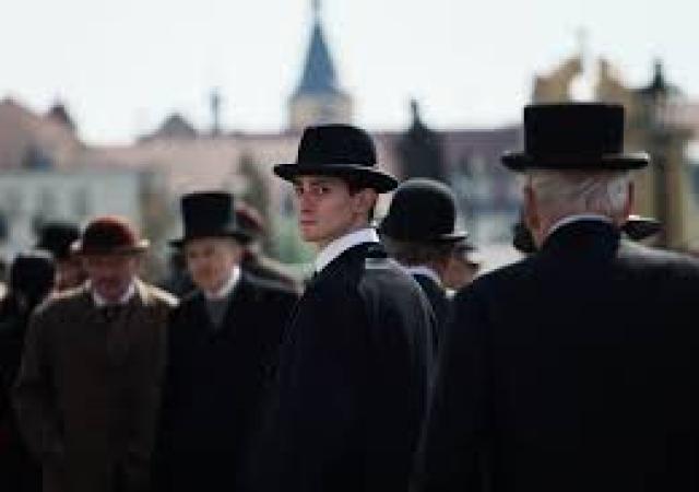 Still from film Franz (2025), men in black bowler hats stand in a crowd.