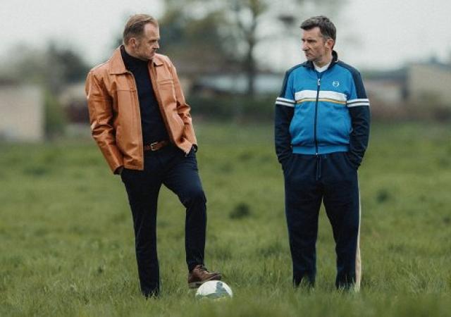 Still from film Sparrow (2024), two men stand on soccer field.