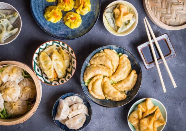 Plates containing different dumpling type foods including gyoza, wontons, and empanadas.