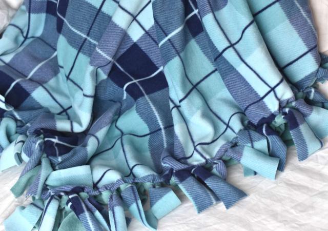 blue plaid tie blanket draped on ground