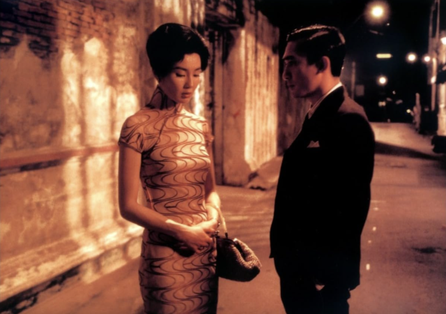 Still from film In the Mood for Love, man and woman stand in a dimly lit street.