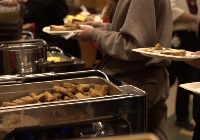 A buffet line featuring a tray of warm sausage and eggs