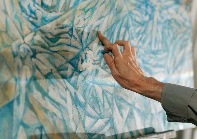 Hand working on a blue pastel drawing.