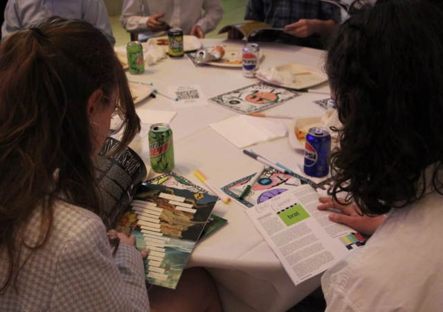 Students sit at table and read magazines together