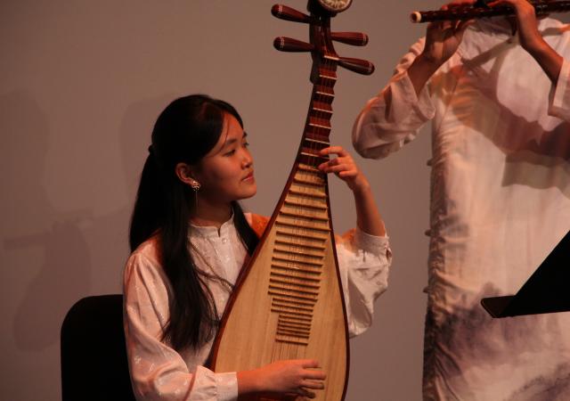 Student playing the Chinese instrument the Pippa while another student is seen playing the flute