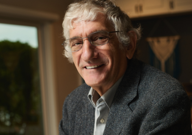 A headshot of John Martinis wearing a button down and grey blazer.