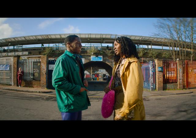 Still from film Rye Lane (2023), a man and a woman stand facing each other on the street.