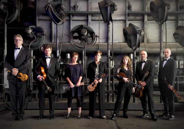 Ukulele Orchestra of Great Britain posed in an industrial setting.