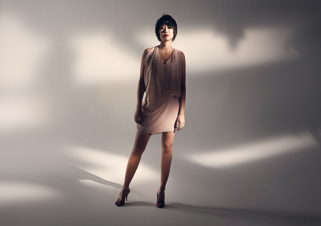 Yuja Wang standing in front of a white, shadow-filled backdrop.