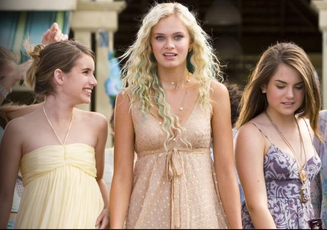 three women standing a row, wearing pale colored halter dresses