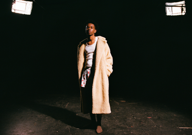 Isaia Huron standing in front of a dark backdrop.