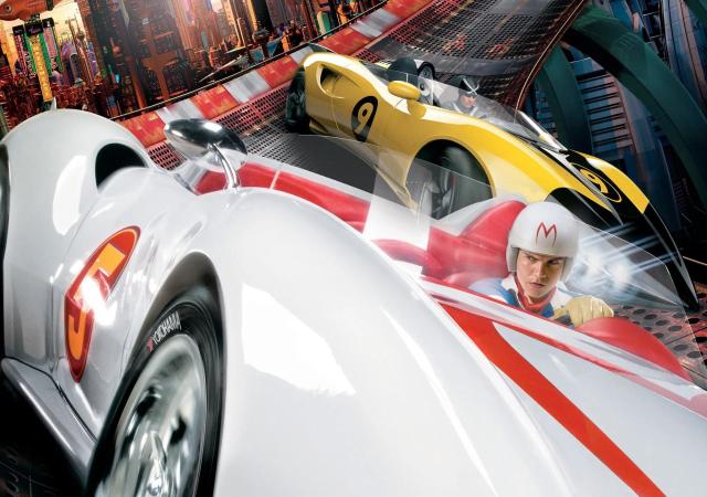 White race car with red trim and a helmeted driver, followed by a yellow race car.