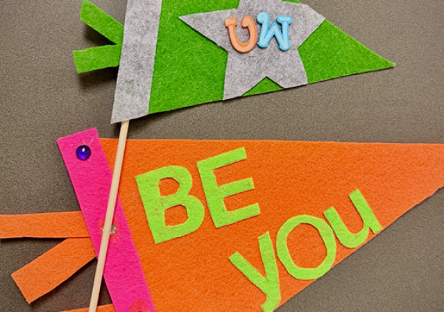 Photo of two pennants made from felt with the words "Be You" and "UW".