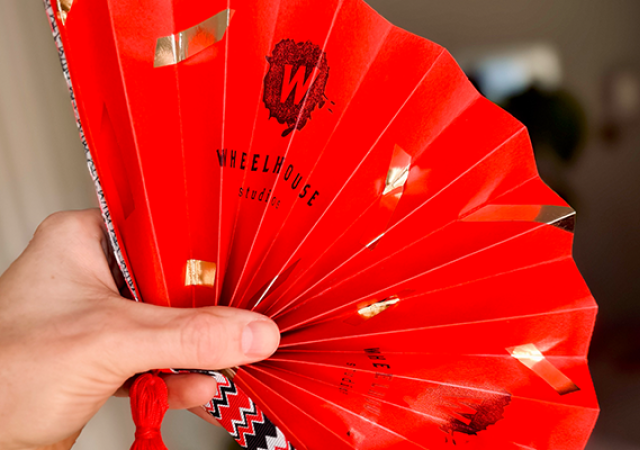 Photo of someone holding a red folding fan.