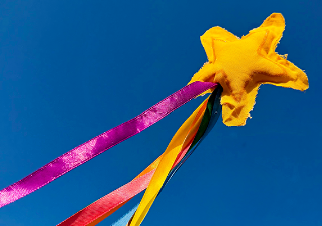 Photo of a wand with a star attached with several colored ribbons in the sky.