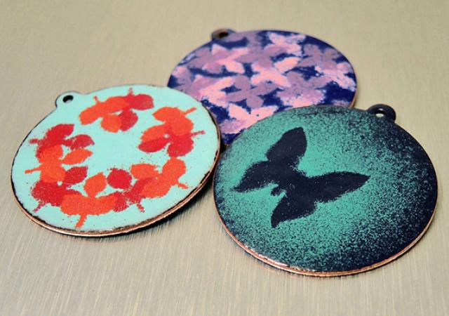 Photo of three different enamel pendants.