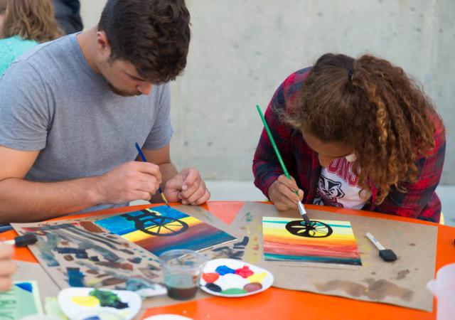 Photo of two people painting on a canvas.
