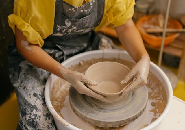 Photo of someone making a clay bowl on a pottery wheel.