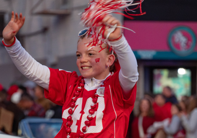 Mini-Marshal Adalyn Howe waves to the crowd lining State Street during the University of Wisconsin-Madison’s Homecoming Parade on Oct. 25, 2024.
