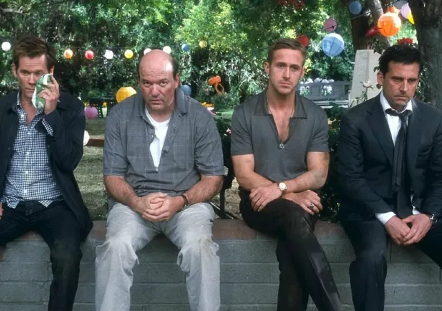 Four men wearing formal-casual attire sit on a ledge looking discouraged, the man on the far left is icing his cheek.