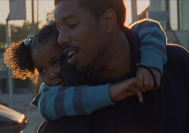 Father dressed in black giving his daughter wearing blue, a piggy back. Both looking frame left.