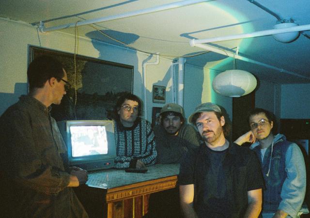 Discus band members standing around a desk with a monitor